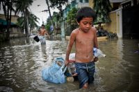 In the aftermath of Typhoon Ketsana (Ondoy), a boy drags some possessions through the flooded streets of Metro Manila.